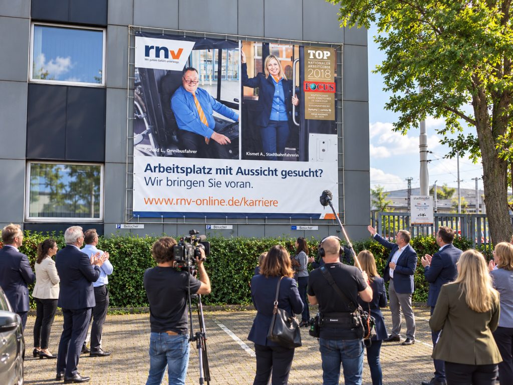 Großformatige Werbeplane für die rnv – von DasMedienwerk produziert und fachgerecht an der Fassade montiert.
